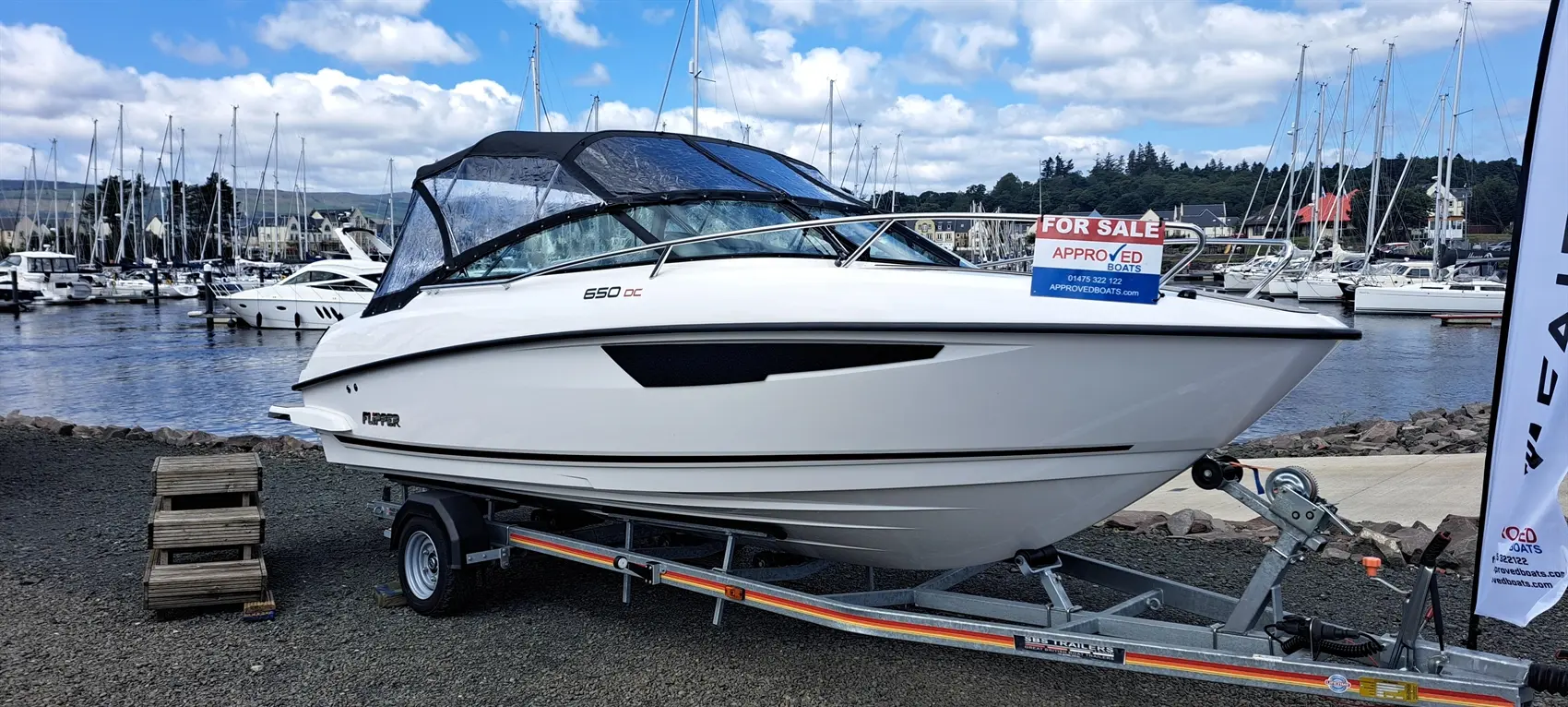 White boat labeled "FLIPPER 650 DC" for sale at a marina, with a sign from Approved Boats and boats in the background.